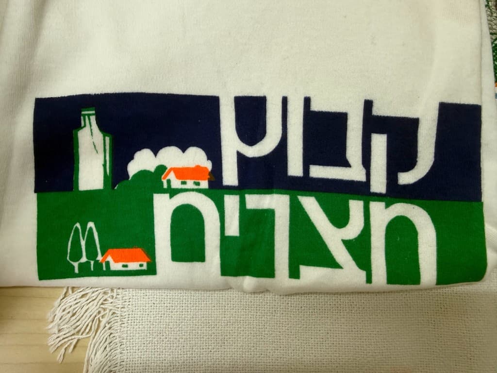 סמל קבוץ חצרים מודפס על חולצה בצבעי כחול, ירוק וכתום